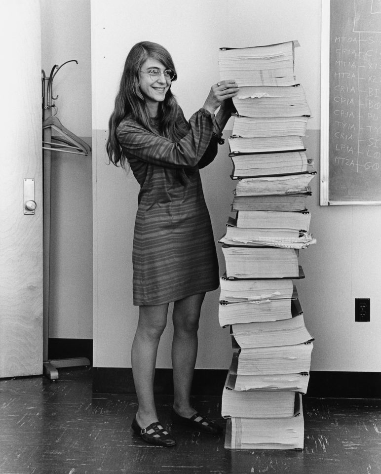 Margaret Hamilton beside printed Apollo guidance software listings, 1969. Restored historical photograph.