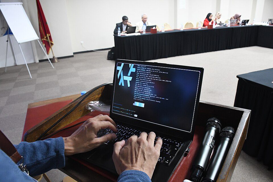 An attendee typing on a laptop at WikiCamp Morocco, 2026. A contemporary setting for human participation in writing.